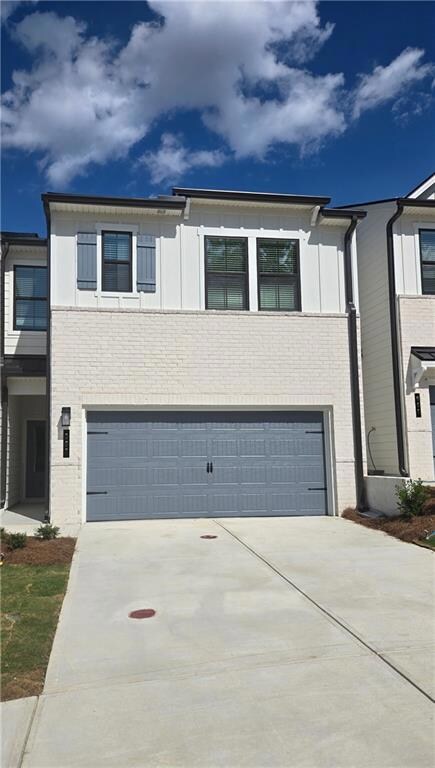 View of front of property featuring a garage, driveway, and brick siding