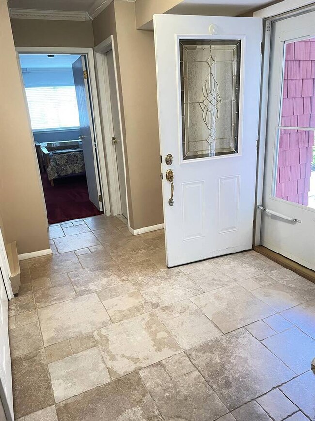 Entrance foyer featuring stone tile floors, crown molding, and baseboards