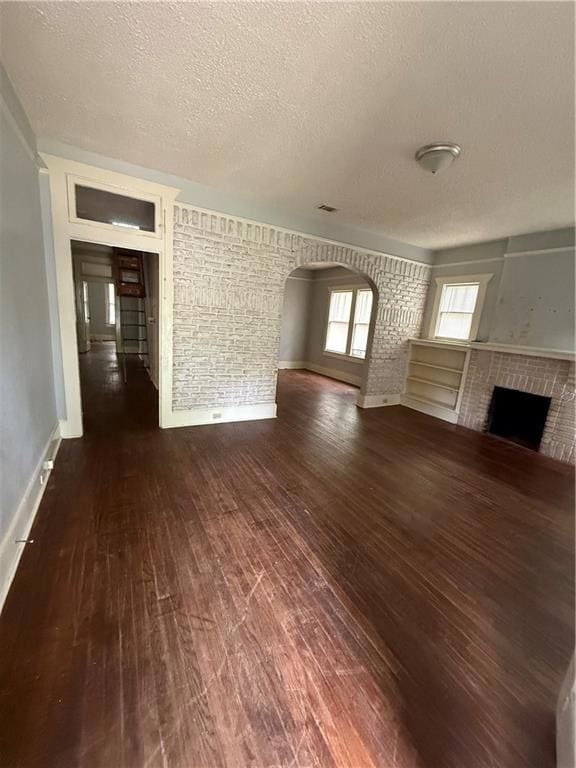 Unfurnished living room with arched walkways, a te