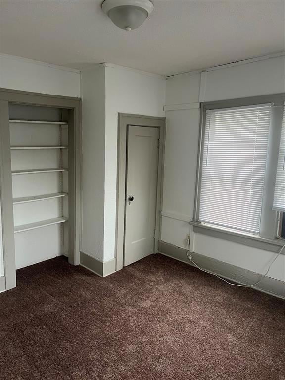 Unfurnished bedroom with dark carpet and a closet