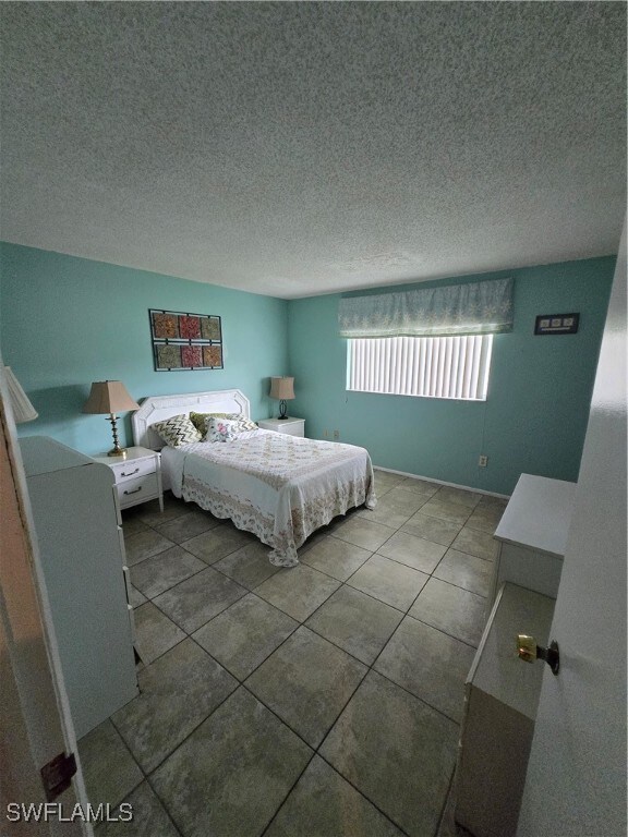 Bedroom with a textured ceiling and tile patterned