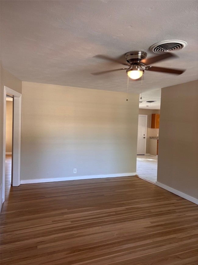Unfurnished room with wood finished floors, a ceiling fan, and a textured ceiling