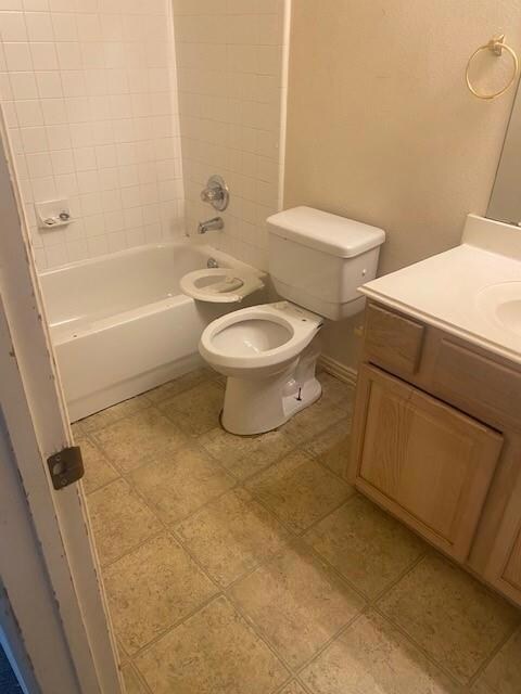 Full bathroom featuring tile patterned floors, vanity, tiled shower / bath, and toilet