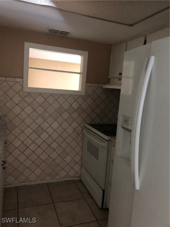 Kitchen featuring refrigerator, tile walls, dark t