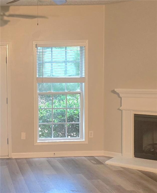 Unfurnished living room featuring wood finished floors, a fireplace, and a textured ceiling
