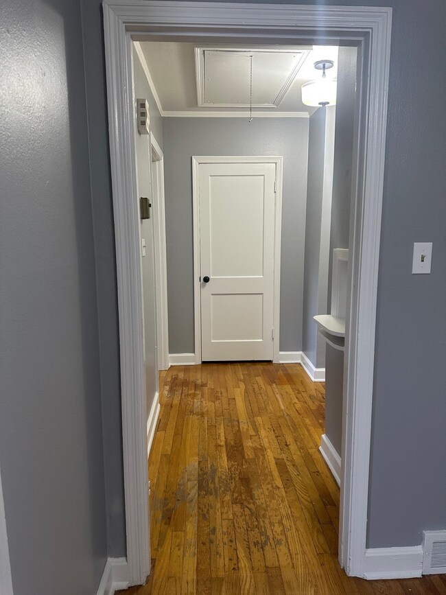 Hallway with attic access, wood-type flooring, bas