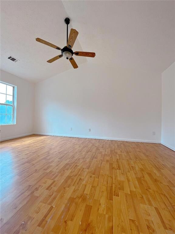Unfurnished room with light wood finished floors, baseboards, vaulted ceiling, and ceiling fan