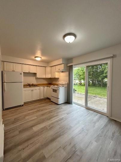 Kitchen with white appliances, light wood-style flooring, and white cabinetry