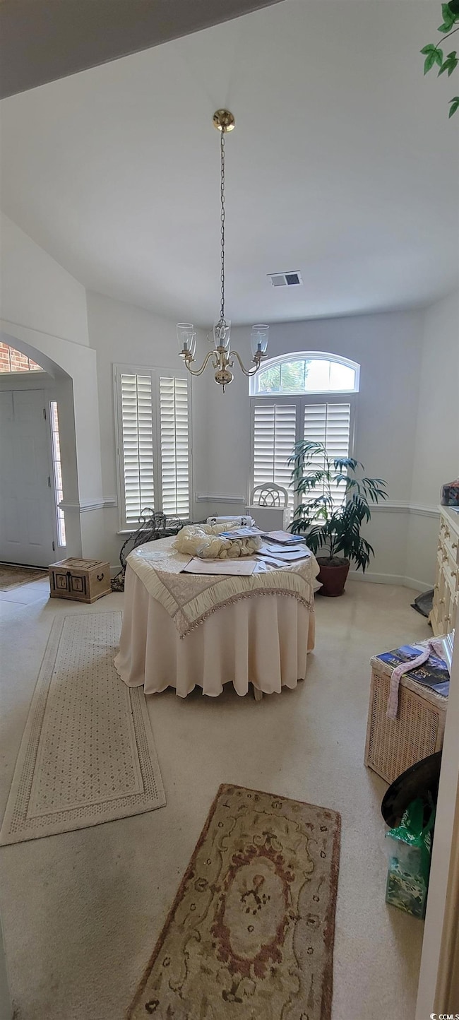 Carpeted Dining room featuring a chandelier and lofted ceiling