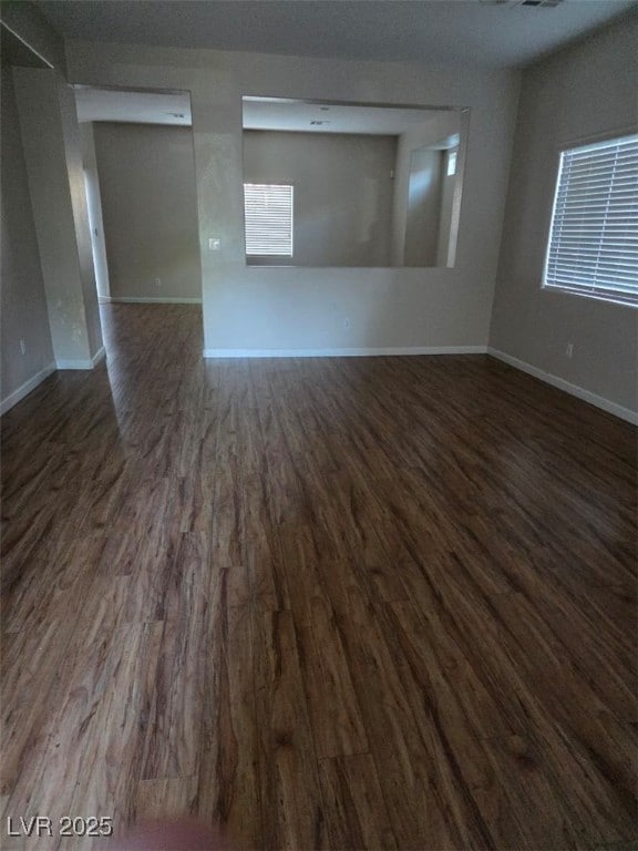 Spare room featuring dark wood-style flooring and baseboards