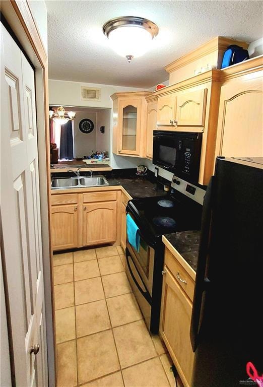 Kitchen featuring light brown cabinetry, black appliances, light tile patterned floors, glass insert cabinets, and a textured ceiling