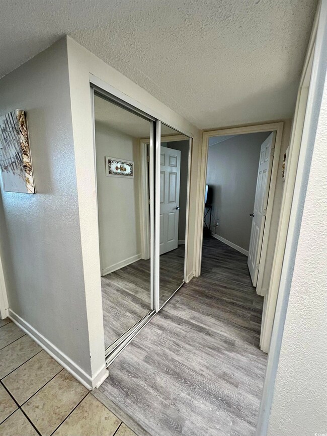 Corridor with a textured ceiling, wood finished fl