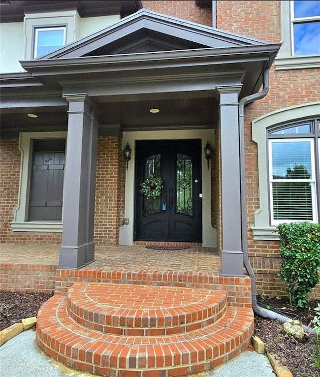 Doorway to property featuring brick siding and french doors