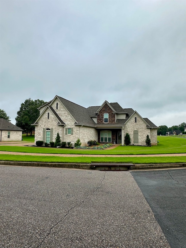 View of front of house featuring stone siding, a front lawn, brick siding, and a shingled roof