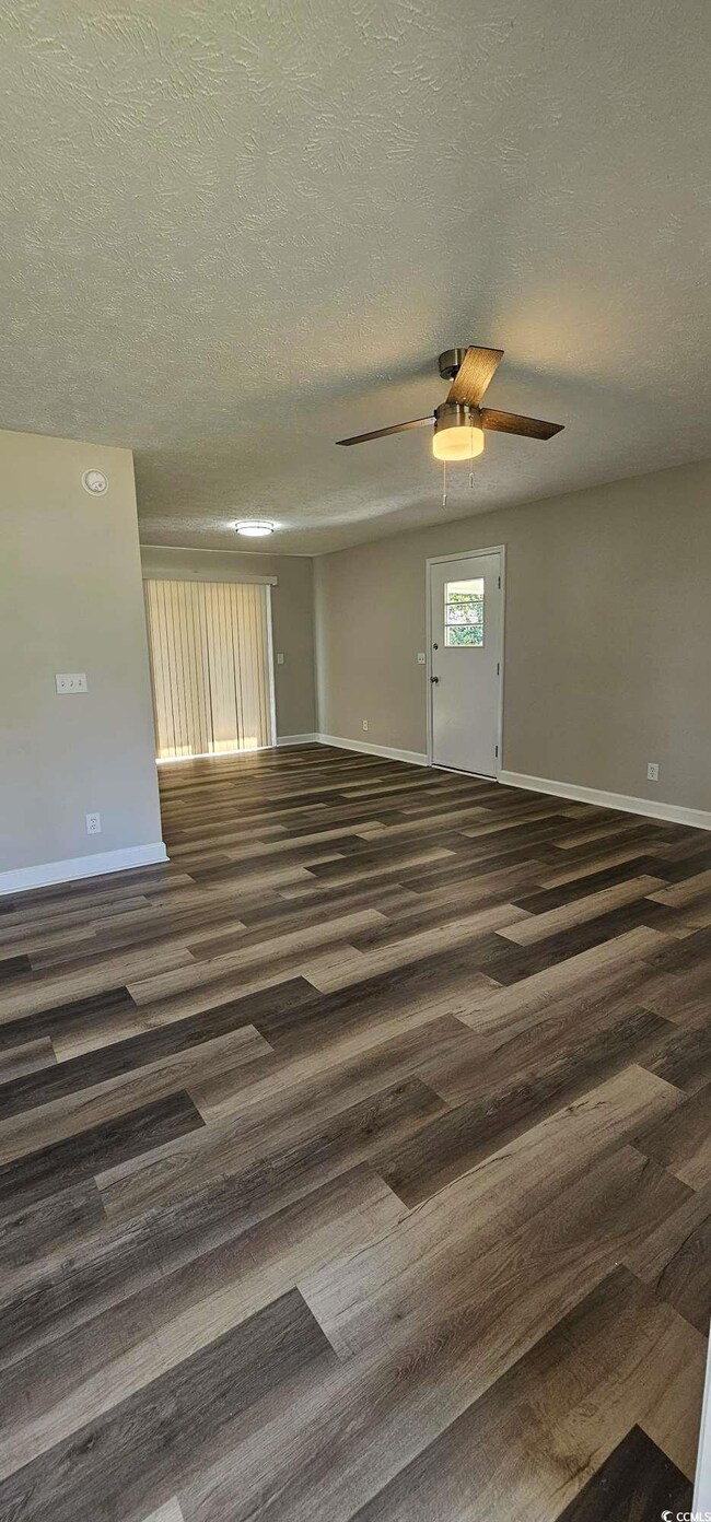 Unfurnished room featuring wood finished floors, ceiling fan, and a textured ceiling