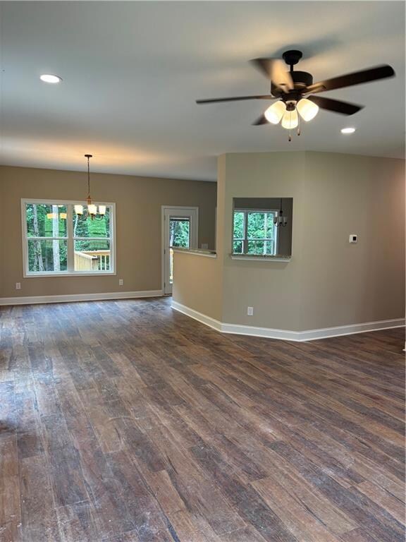 Empty room featuring dark wood-type flooring, a chandelier, healthy amount of natural light, and recessed lighting