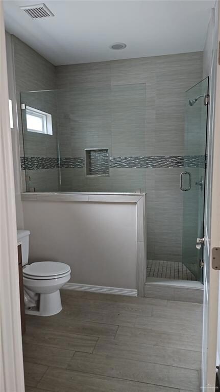 Full bathroom featuring a stall shower, vanity, wood finished floors, and tile walls
