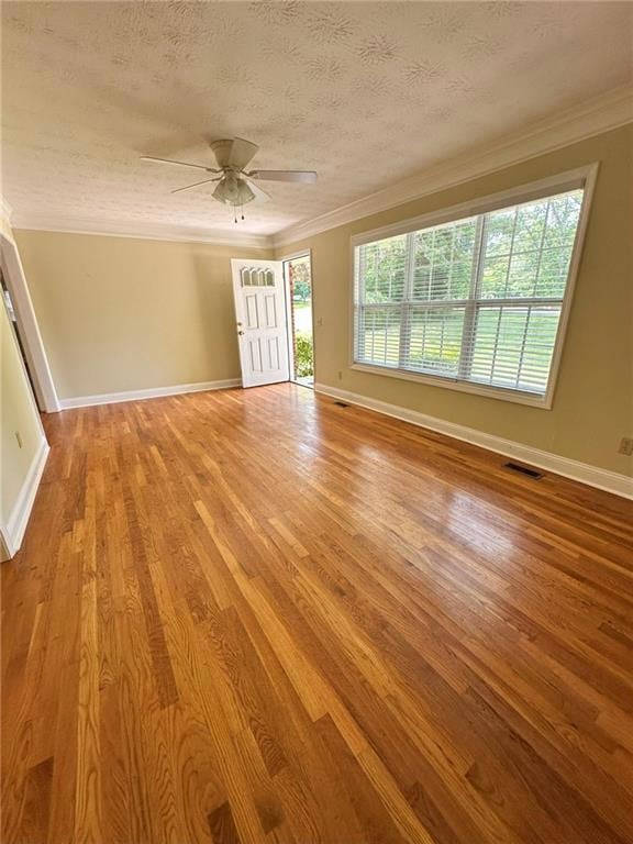 Empty room with crown molding, ceiling fan, baseboards, light wood-style flooring, and a textured ceiling