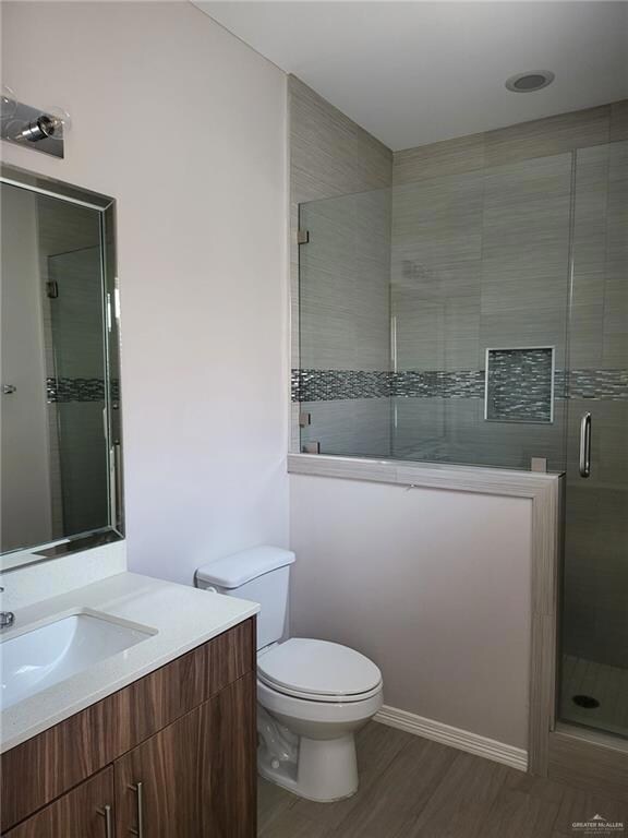 Full bathroom with vanity, a stall shower, and wood finished floors