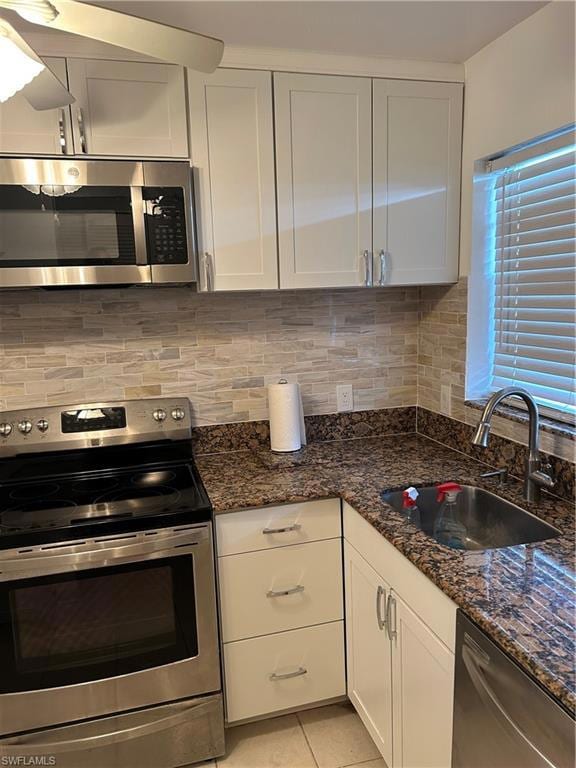 Kitchen with stove, dishwasher, white cabinetry, and tasteful backsplash