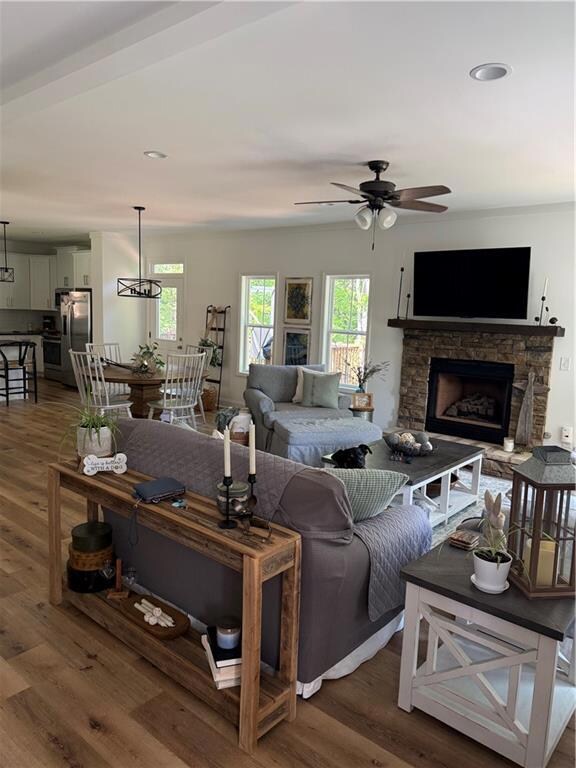 Living room featuring ceiling fan, wood finished floors, a stone fireplace, and recessed lighting