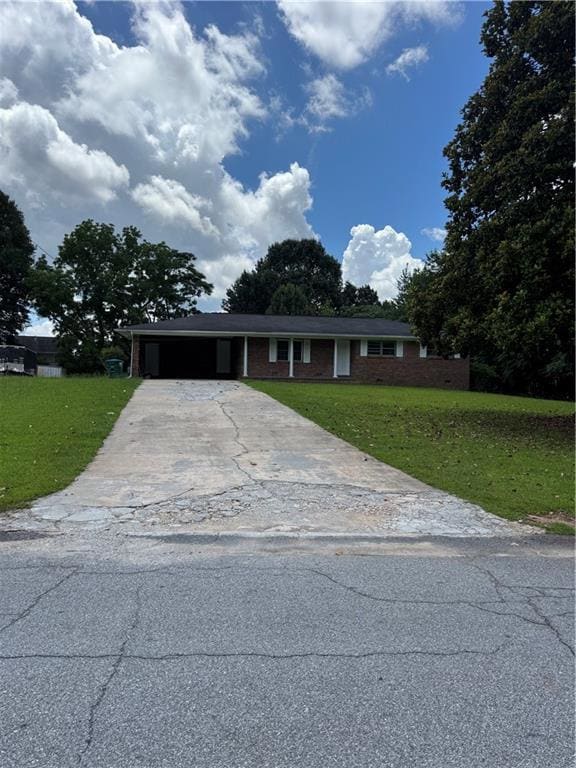 View of front of home with a front yard, concrete driveway, and a carport