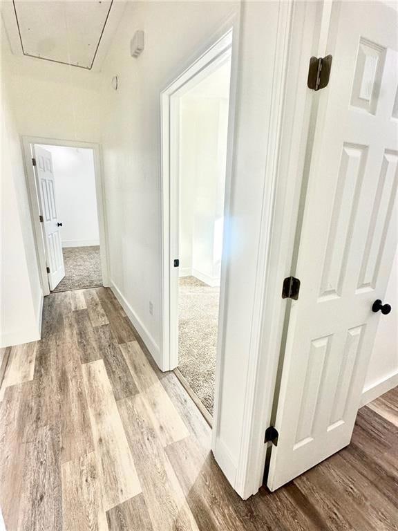 Hall with attic access and light wood finished floors