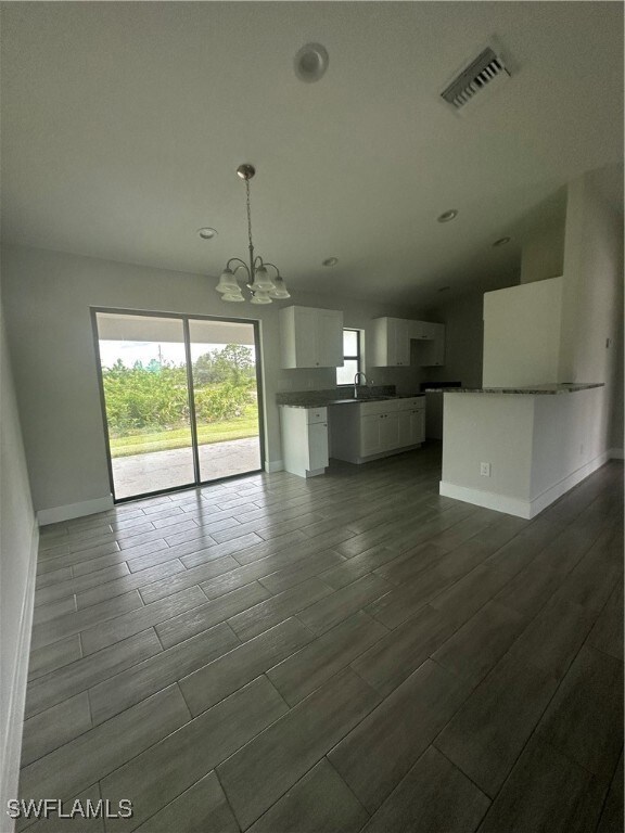 Unfurnished living room with a chandelier, wood fi