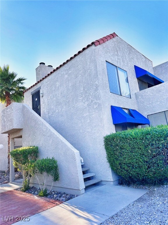 View of side of home with stucco siding, a chimney