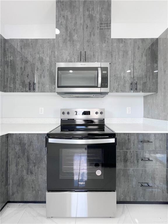 Kitchen with modern cabinets, marble finish floor, appliances with stainless steel finishes, and gray cabinetry