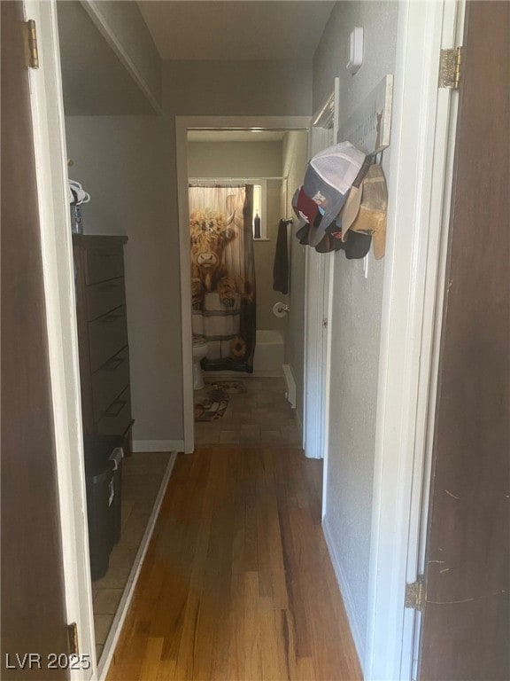 Hallway with hardwood / wood-style flooring and ba