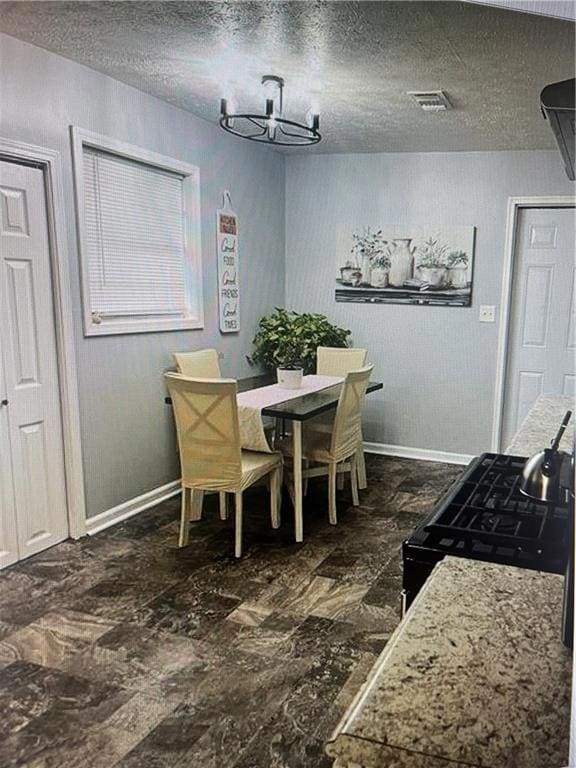 Dining area featuring a textured ceiling and dark stone finish flooring