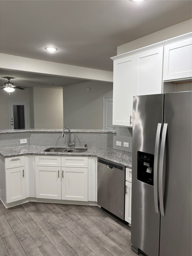 Kitchen featuring refrigerator, white cabinets, dishwashing machine, light wood finished floors, and recessed lighting