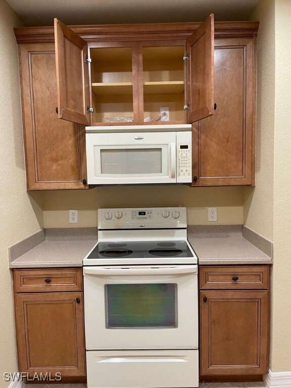 Kitchen featuring white appliances, light countert
