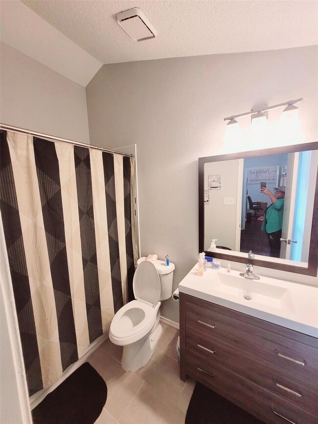 Bathroom with a textured ceiling, vanity, vaulted 