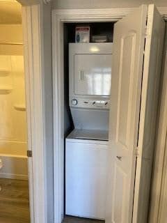 Laundry area with stacked washer / drying machine and wood-type flooring