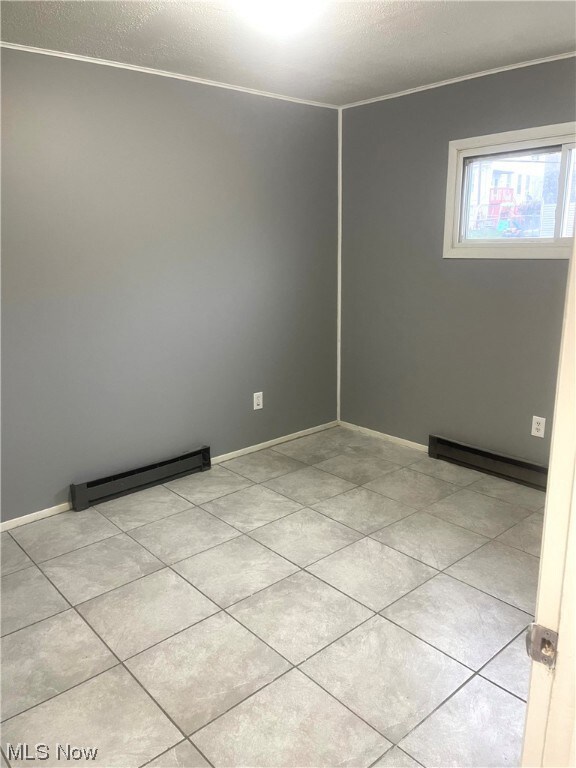 Tiled empty room featuring a baseboard radiator