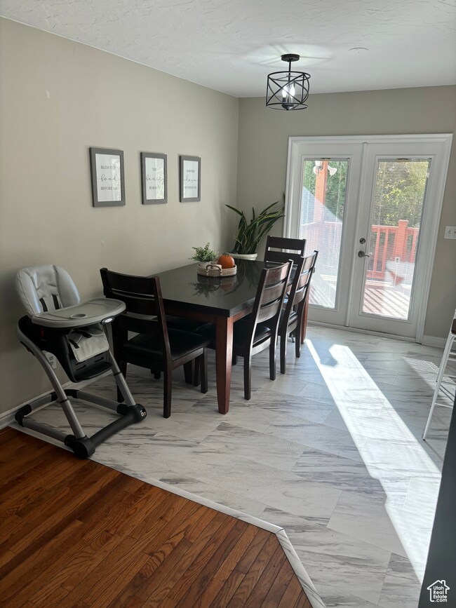 Dining room featuring a chandelier, french doors, a textured ceiling, and LVP floors