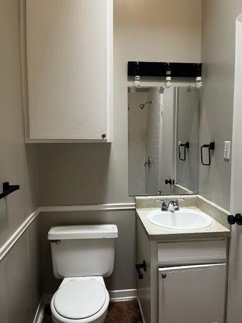 Bathroom featuring vanity, toilet, and baseboards
