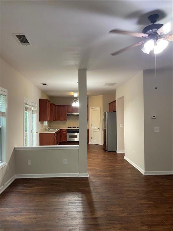 Kitchen featuring ceiling fan, dark wood-type flooring, freestanding refrigerator, light countertops, and under cabinet range hood