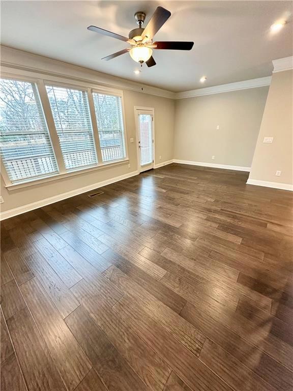 Empty room with dark wood-type flooring, crown mol