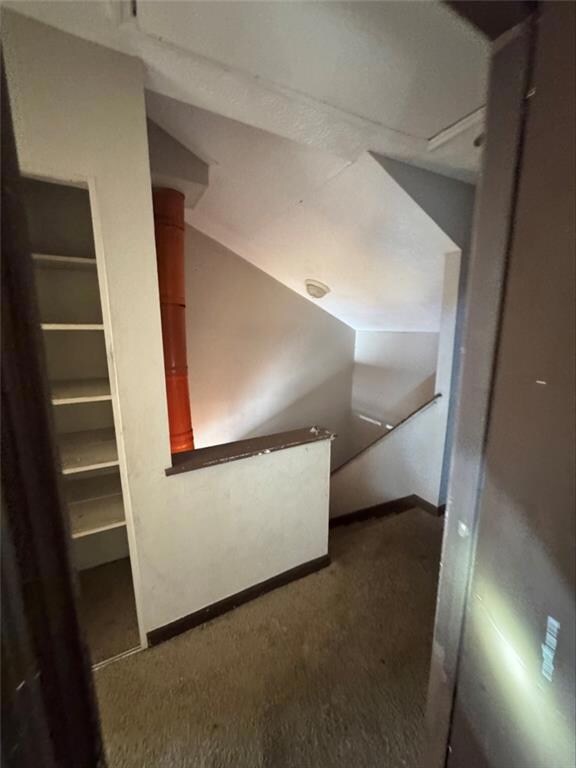 Bonus room with lofted ceiling and dark carpet