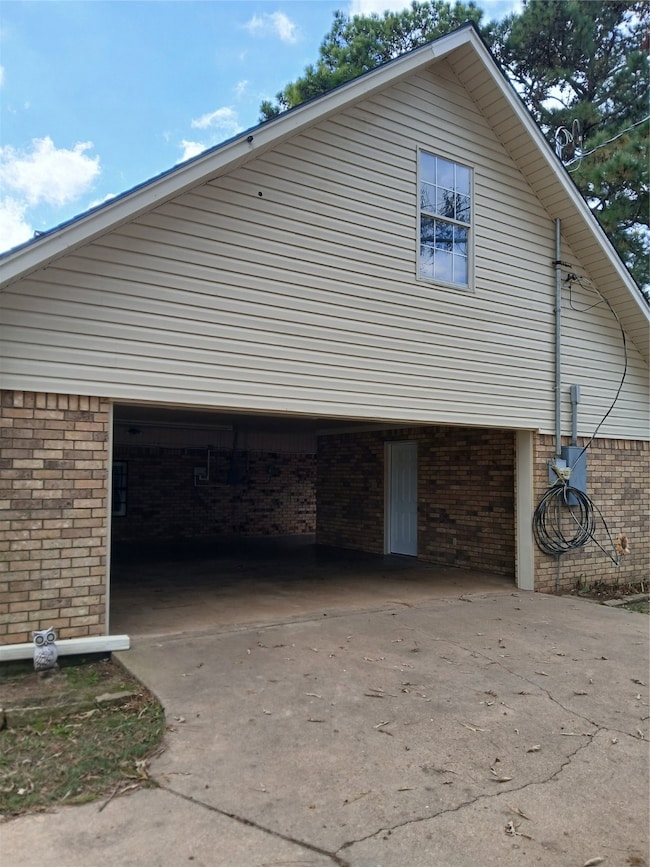 View of side of home featuring brick siding, driveway, and a garage