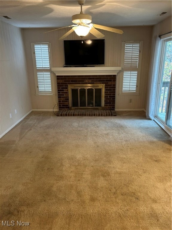 Unfurnished living room featuring a brick fireplace, a ceiling fan, and carpet flooring