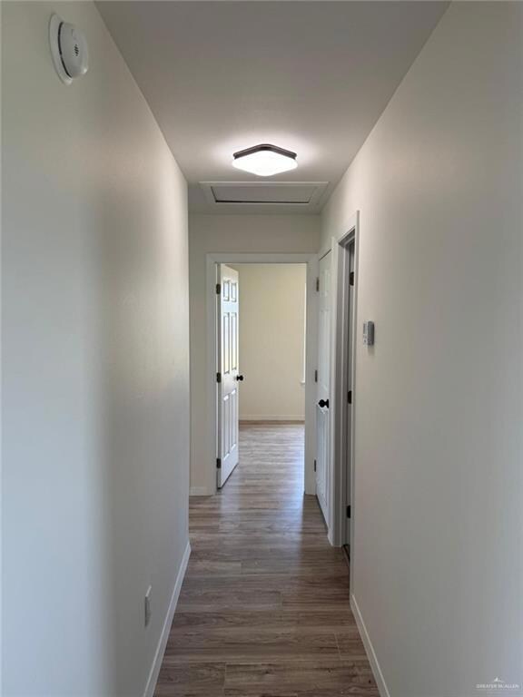 Hallway with attic access and wood finished floors