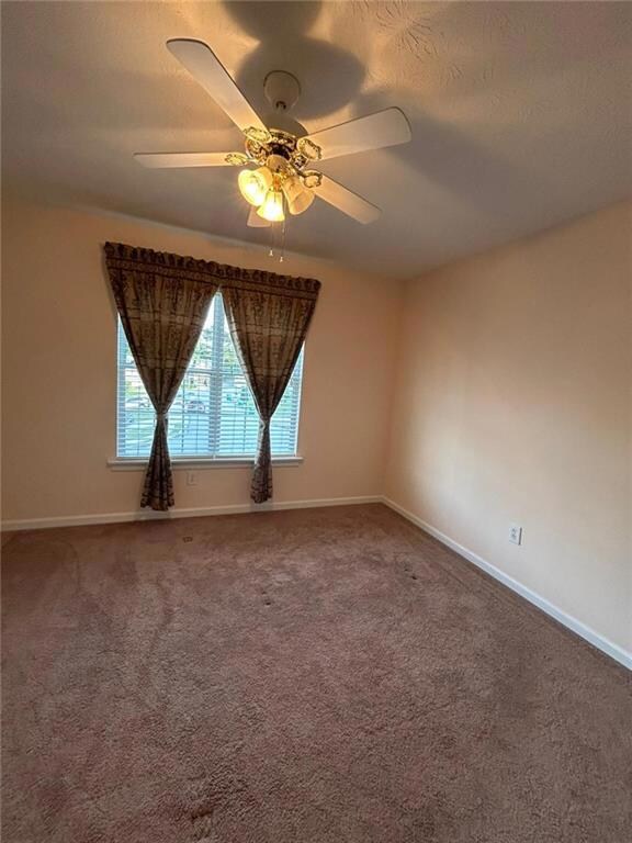 Unfurnished room with carpet floors, a ceiling fan, and a textured ceiling