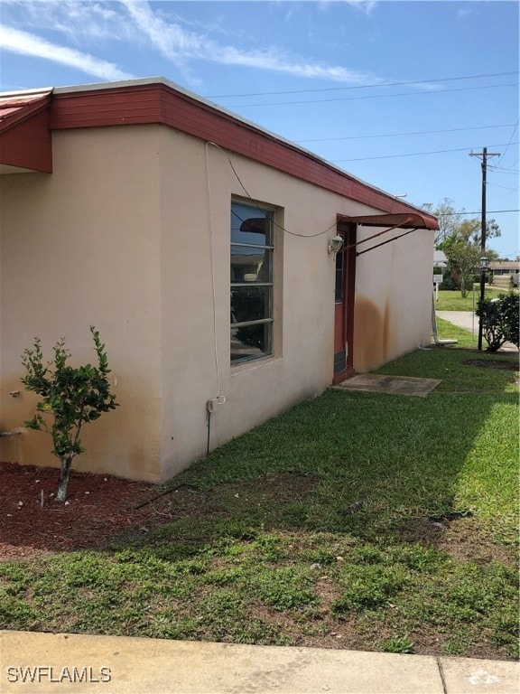 View of side of property with a lawn
