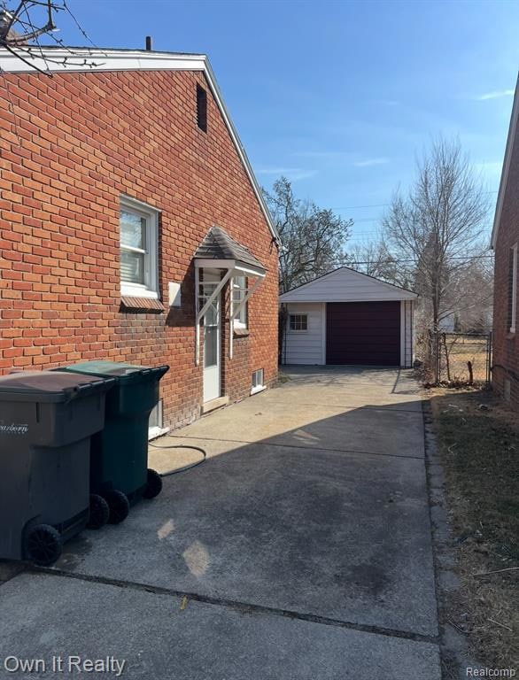 View of home's exterior featuring brick siding, an outdoor structure, and a detached garage