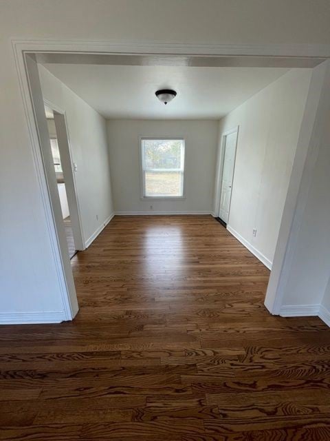 Unfurnished room featuring dark wood-style flooring and baseboards
