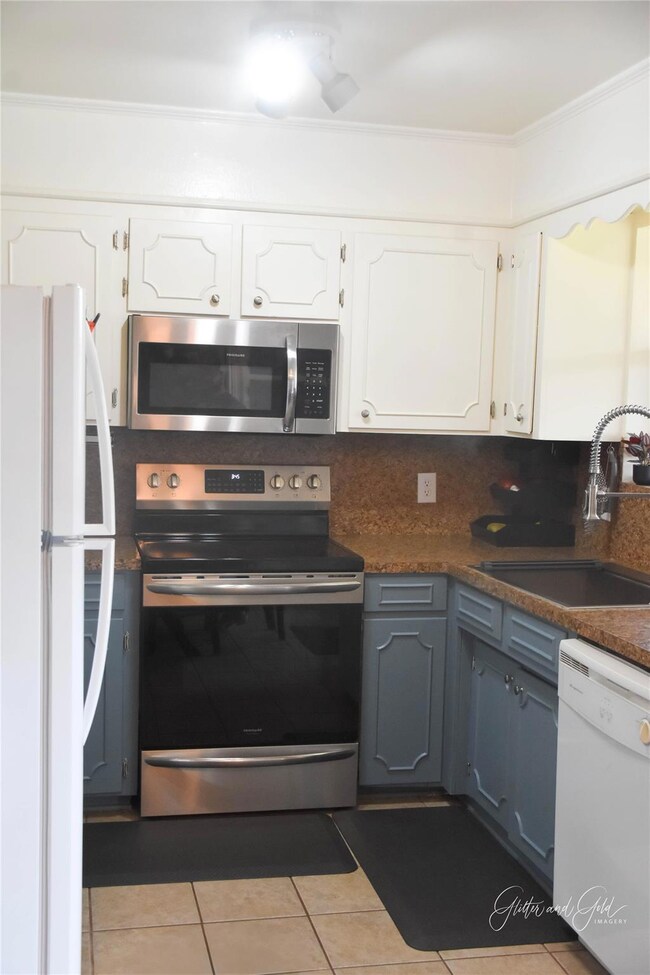 Kitchen featuring white cabinets, a sink, stainles